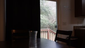 A dark room with a glass on a table, a chair, a wooden railing outside, and a wall sign that says 'Family.'