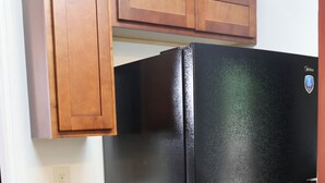 A kitchen with wooden cabinets, a granite countertop, and a black refrigerator.