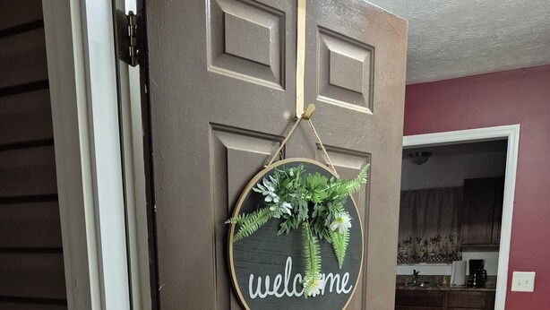 A brown door with a 'welcome' sign and a small plant decoration.