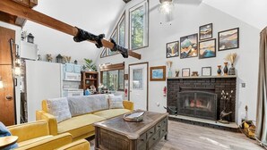 Ein gemütliches Wohnzimmer mit Kamin, gelben Sofas und einem Holztisch.
