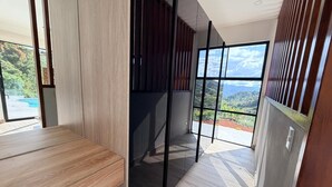 Een moderne kamer met een houten bank, een schuifdeur en een groot raam met uitzicht op een bergachtig landschap.