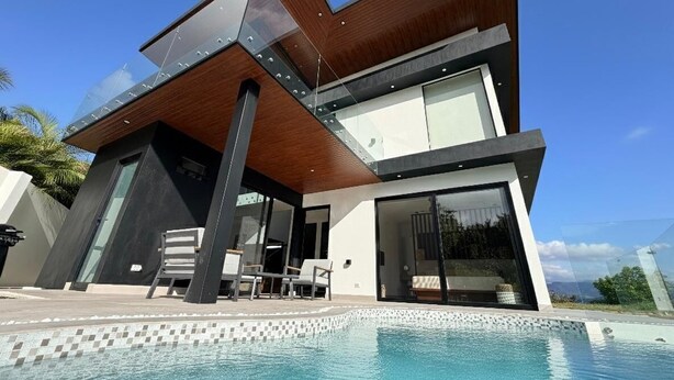 Een modern huis met twee verdiepingen en een zwembad ervoor.