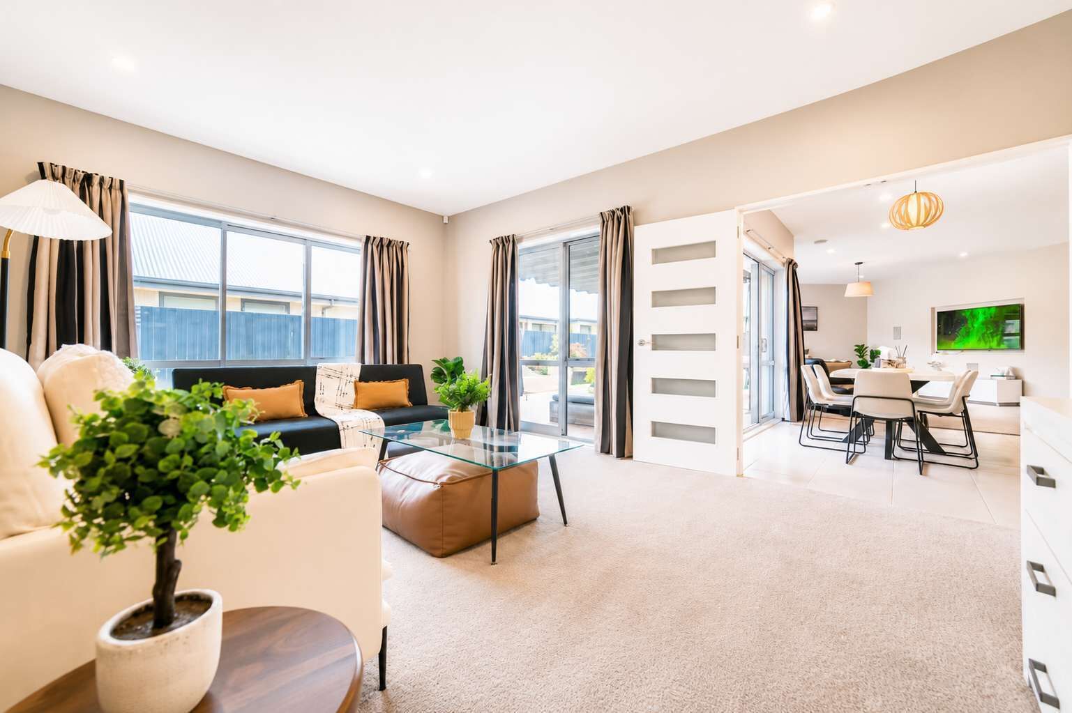 A modern living room with a sofa, coffee table, and a dining area with chairs and a table.