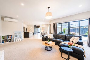 A modern living room with a black leather sofa, a coffee table, and a bookshelf.