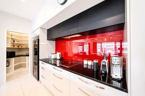 Eine moderne Küche mit schwarzer Arbeitsplatte, weißen Schränken und einer roten Spritzschutzwand.