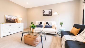 A modern living room with a sofa set, a coffee table, a side table, a lamp, and a painting on the wall.