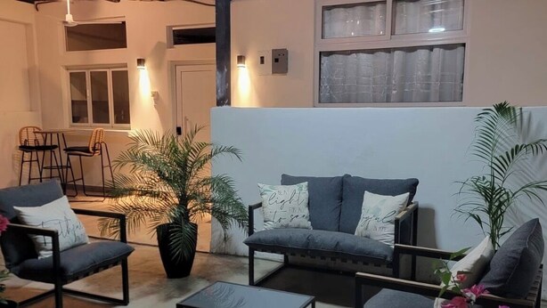 A living area with a sofa, two armchairs, a coffee table, and potted plants.
