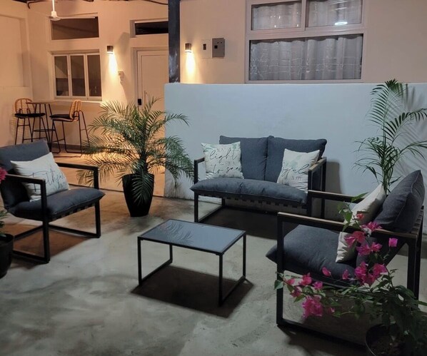 A living area with a sofa, two armchairs, a coffee table, and potted plants.