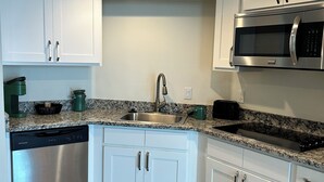 Una cocina moderna con armarios blancos, electrodomésticos de acero inoxidable y encimera de granito.