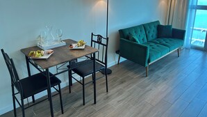 Una habitación moderna con una mesa de comedor, sillas, un sofá verde y dos lámparas de pie.
