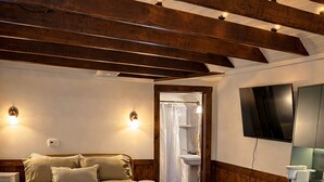 Un dormitorio con cama, mesitas de noche, televisión y un escritorio con silla.