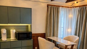 Una cocina acogedora con microondas, cafetera y una mesa de madera con dos sillas.