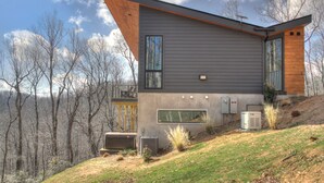 A modern house with a sloped roof, large windows, and a small deck. - Modern Mountain Sanctuary on 37 Private Acres; Views, Trails, Hot Tub,Workspaces (Black Mountain)