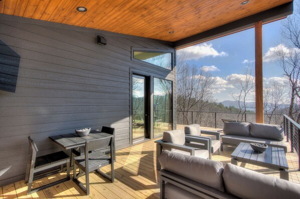 A modern outdoor patio with a wooden ceiling, grey walls, and a view of the mountains. - Modern Mountain Sanctuary on 37 Private Acres; Views, Trails, Hot Tub,Workspaces (Black Mountain)