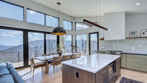Una cucina moderna con ampie finestre, un'isola centrale e un'area pranzo con vista sulle montagne.