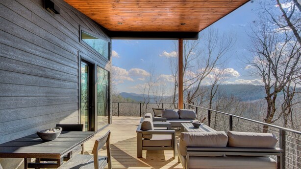 Un terrazzo in legno con posti a sedere all'aperto e vista sulle montagne.