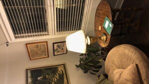 Une pièce dotée d’un ventilateur de plafond, d’une lampe, d’une chaise et d’œuvres d’art accrochées au mur.