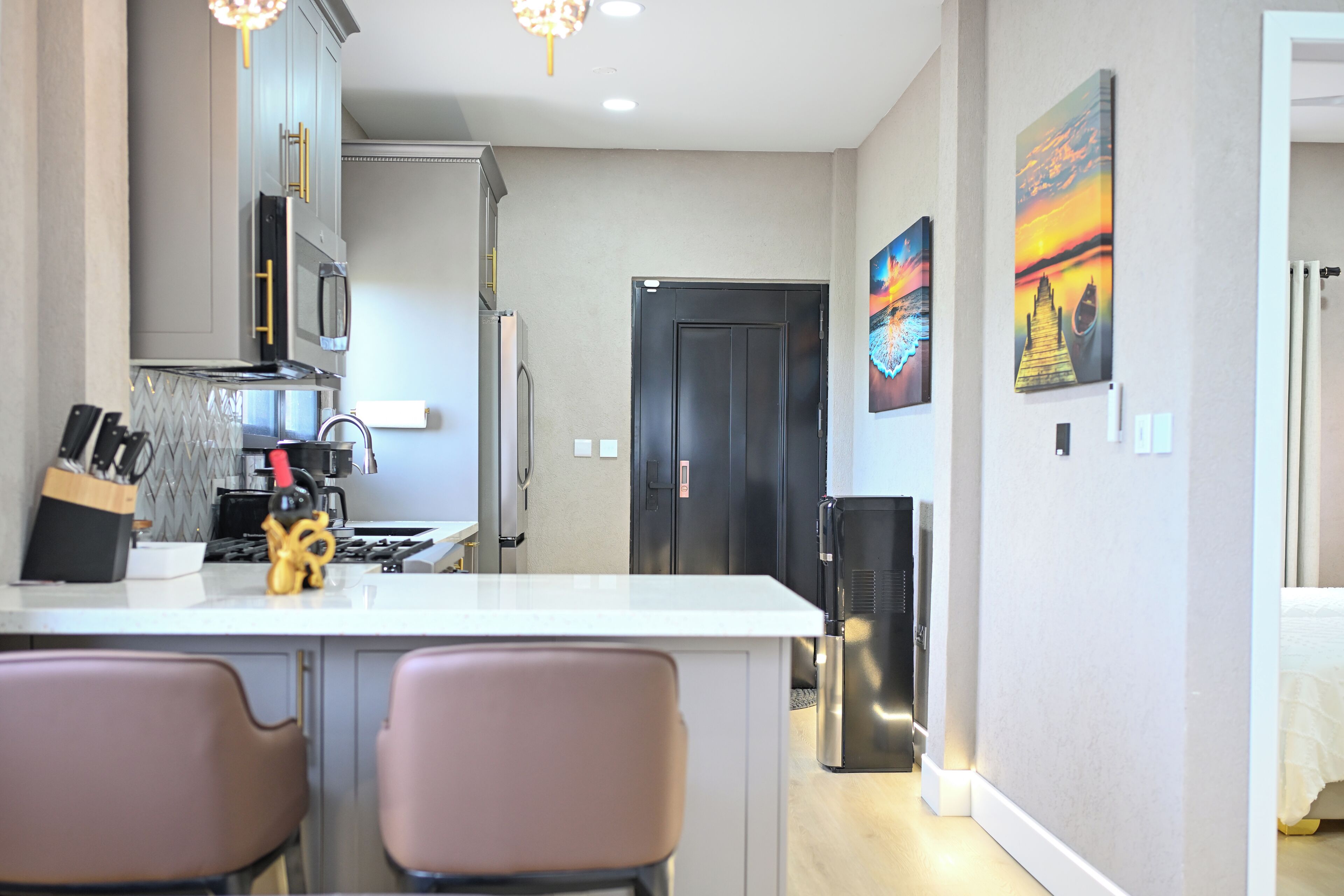 A modern kitchen with a central island, stainless steel appliances, and a dining area with two chairs.