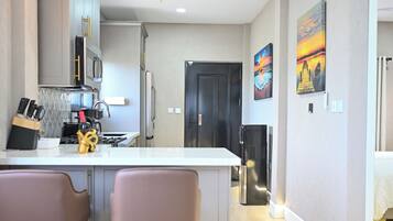 A modern kitchen with a central island, stainless steel appliances, and a dining area with two chairs.