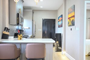 A modern kitchen with a central island, stainless steel appliances, and a dining area with two chairs. - 1BR Connected Villa-MSV, Sea Views – Couples, Solo Travelers (Saint George)