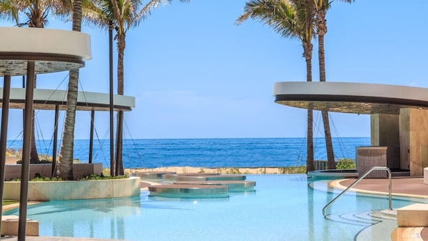A pool area with clear blue water, palm trees, and a view of the ocean. - Infinity Oceanview 2 Bedroom Suite - The Langham (Surfers Paradise)