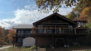 Ein zweigeschossiges Haus mit einer großen Garage, einem überdachten Außenbereich und einem Balkon.