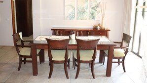 A dining area with a wooden table and chairs, a cabinet, and a window with curtains. - Beautiful 2-bedroom condo with AC in Tamarindo (Tamarindo)