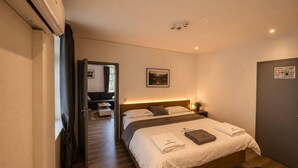 A hotel room with a bed, bedside table, and a view of the hallway.