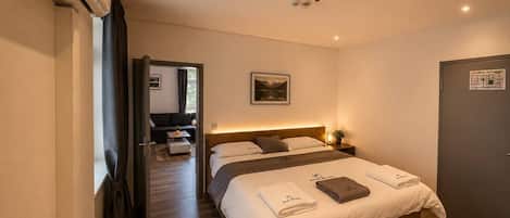 Una habitación de hotel con cama, mesita de noche y vista al pasillo.