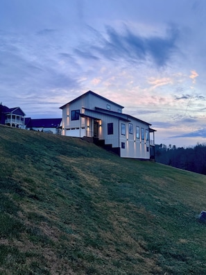 A modern house with a flat roof, large windows, and a staircase leading up to the entrance. - Contemporary 3-bdr house, 20-min downtown AVL & 30 min to Smokies! WNC Sunsets! (Leicester)