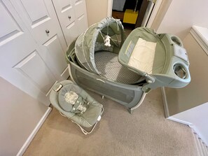 Ein Babywagen mit passendem Kinderwagenkorb, beide in einer neutralen Farbe, stehen in einer Diele mit Teppichboden. Im Hintergrund ist eine weiße Tür zu sehen.