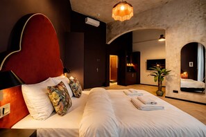 A hotel room with a large bed, a red headboard, and a mirror.