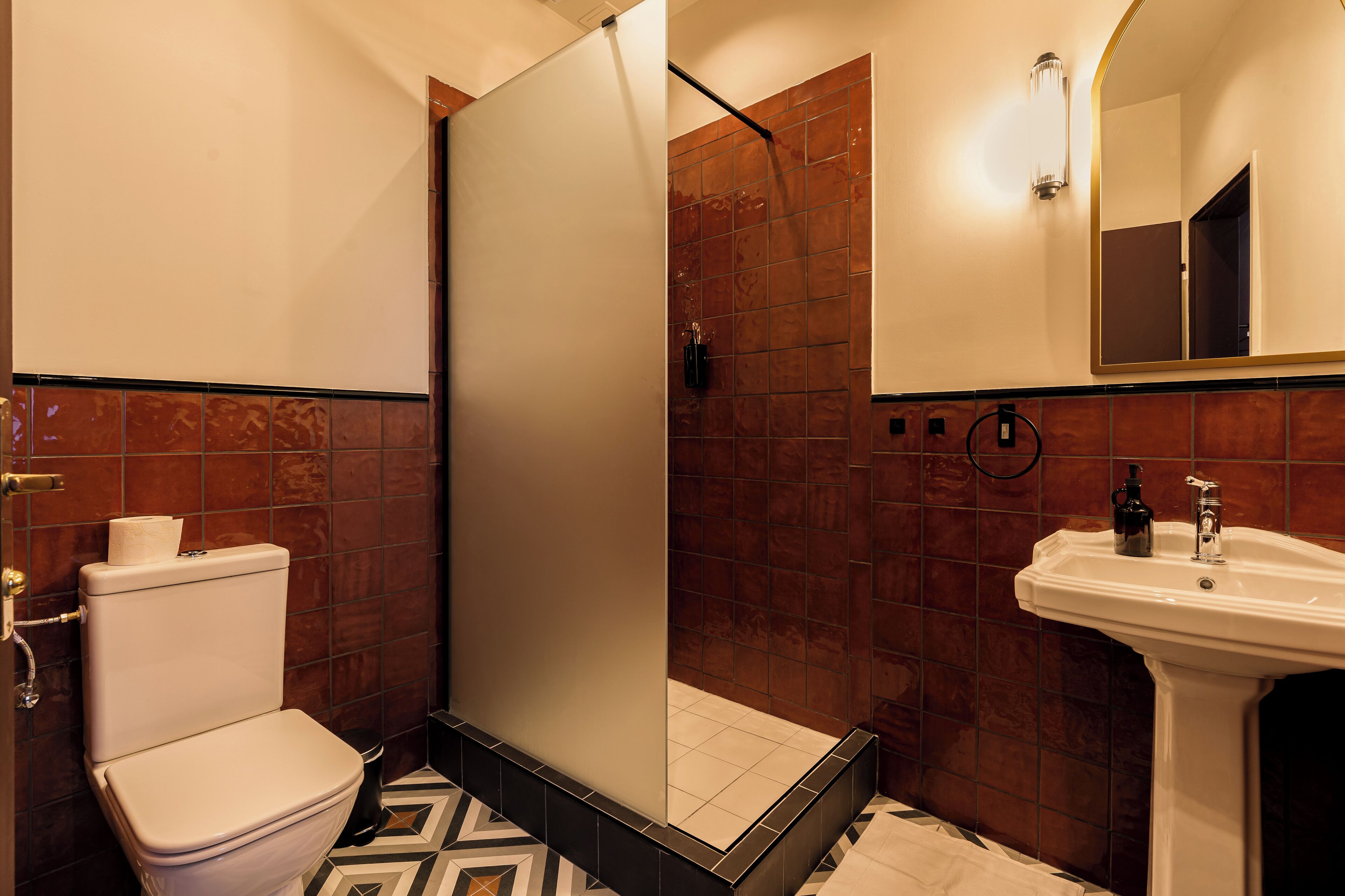 A bathroom with a toilet, a shower enclosure, and a sink.
