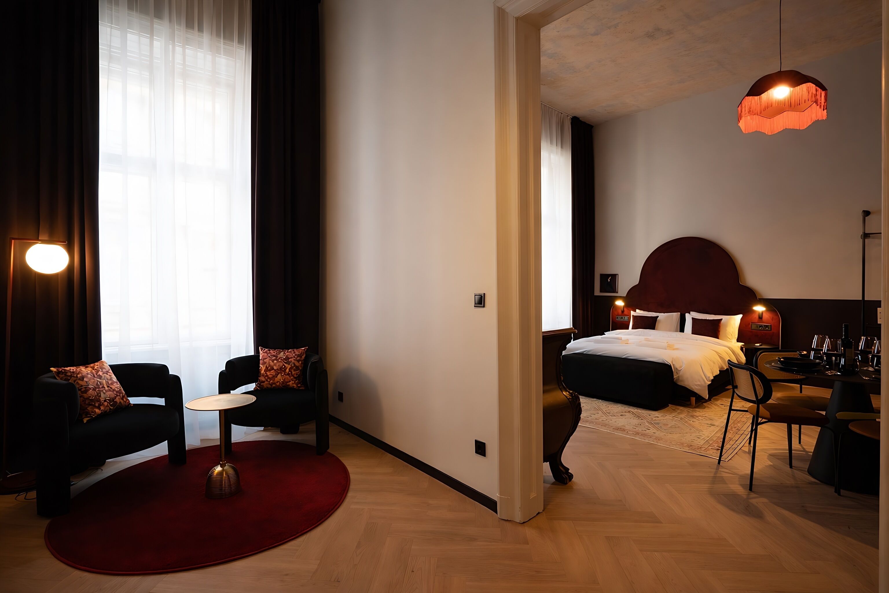 Une chambre d’hôtel moderne avec un grand lit, un bureau avec une chaise, un canapé et un tapis rouge.