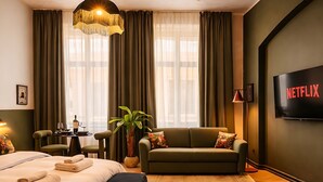 A hotel room with a bed, a sofa, a TV, and a large window with curtains. - Maroon & Moss Residence (Budapest)
