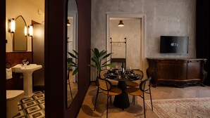 A modern dining area with a round table, chairs, and a TV mounted on the wall. - Maroon & Moss Residence (Budapest)