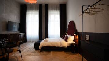 A modern hotel room with a large bed, a flat-screen TV, a desk with a chair, and a large window with curtains.