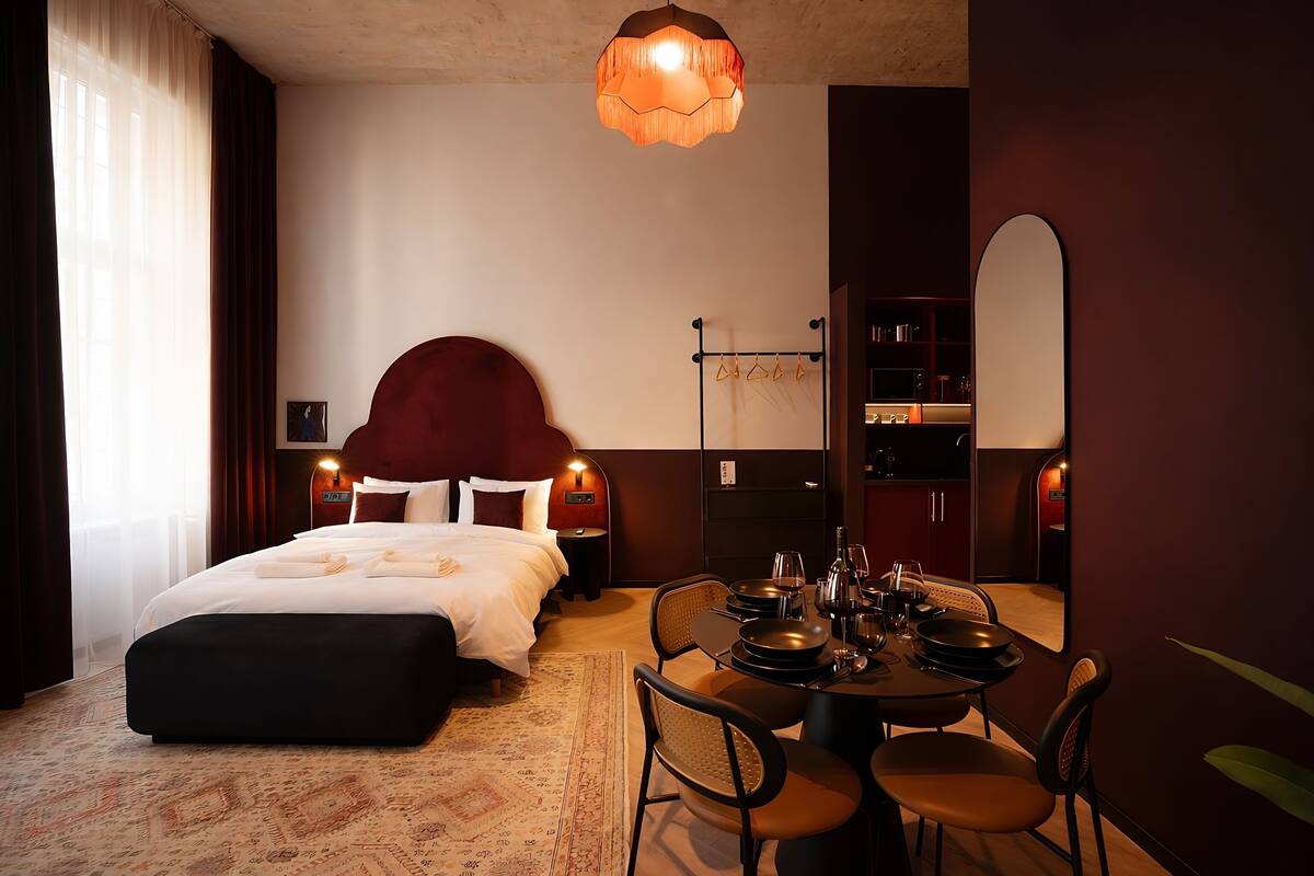 Une chambre d’hôtel comprenant un lit, une table de chevet, une lampe et un coin repas avec des chaises et une table.