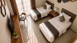 Ein Hotelzimmer mit zwei Betten, einem Schreibtisch mit Stuhl, einem Fernseher und einer Topfpflanze.