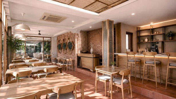 Ein Restaurant mit Holztischen und -stühlen, einer Ziegelwand und einer Bar.