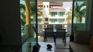 A modern living room with a glass coffee table, a sofa, and a dining area with chairs and a table. - APARTMENT IN ACAPULCO DIAMOND ZONE (Acapulco de Juárez)