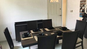 A dining area with a rectangular table, black chairs, and a white door with a window. - APARTMENT IN ACAPULCO DIAMOND ZONE (Acapulco de Juárez)
