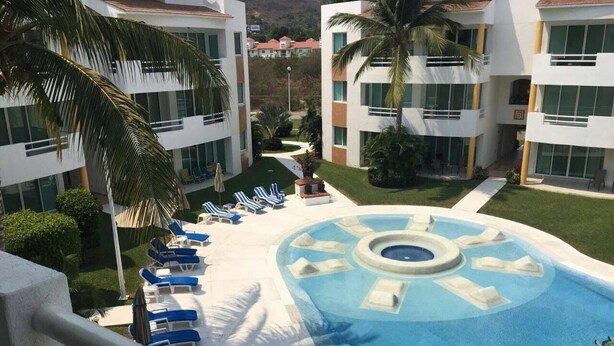 A pool area with lounge chairs and a central water feature. - APARTMENT IN ACAPULCO DIAMOND ZONE (Acapulco de Juárez)