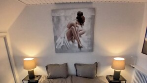 Una camera da letto con un letto grande, due comodini con lampade, una TV a parete e un quadro sopra il letto.