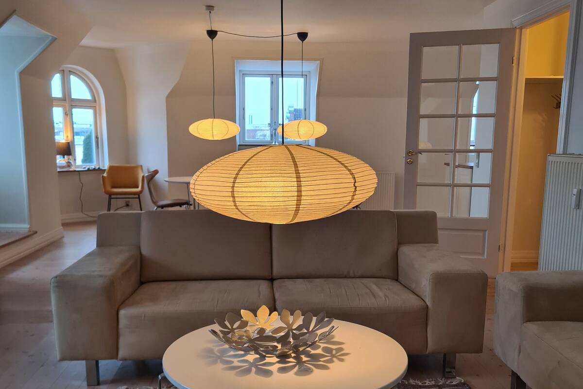 A modern living room with a large sofa, a round coffee table, and a unique hanging light fixture.