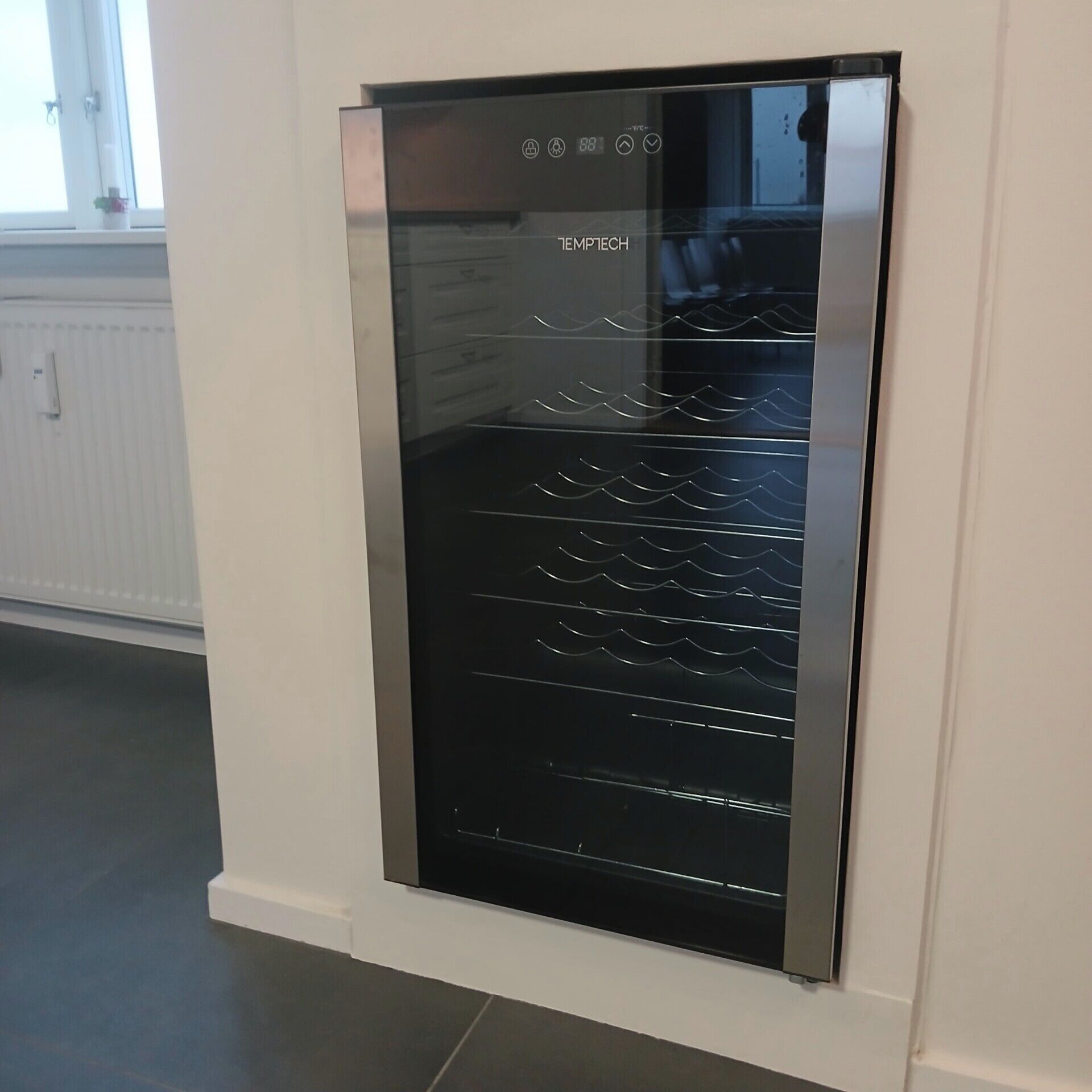 A modern kitchen with a built-in stainless steel refrigerator and a white tiled backsplash.