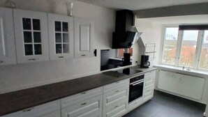 Cucina moderna con mobili bianchi, cappa aspirante nera e finestra con vista sugli edifici.