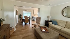Ein geräumiges Wohnzimmer mit einer Couch, Hocker und einem Essbereich mit Stühlen und Tisch.