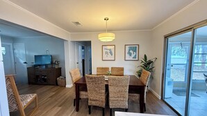 Ein Essbereich mit Tisch, Stühlen und einem Fernseher im Hintergrund.