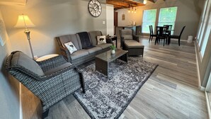 A cozy living room with a sofa, armchairs, a coffee table, and a dining area with chairs and a table.